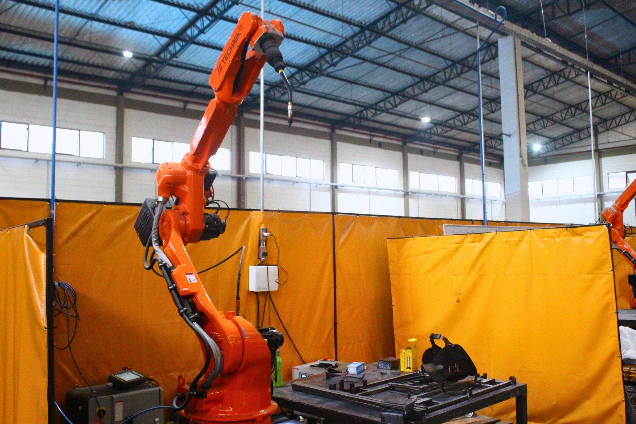 Robô de solda industrial laranja na fábrica da Estrutálica